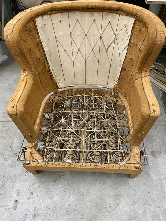 Stripped armchair with exposed seat springs, burlap, and a marked back panel